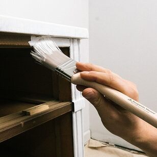 Applying primer to the surface of a cabinet in a room with white walls. Applying primer to the surface of a cabinet in a room with white walls.