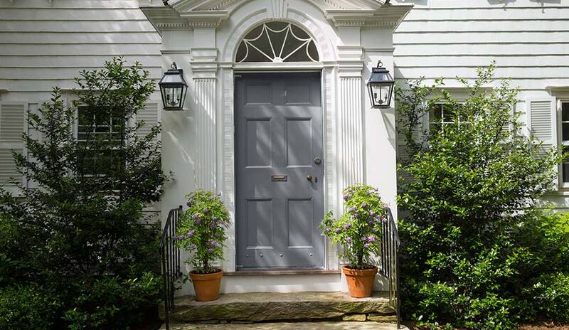 A colonial style front entrance with gray-painted front door and stone steps.