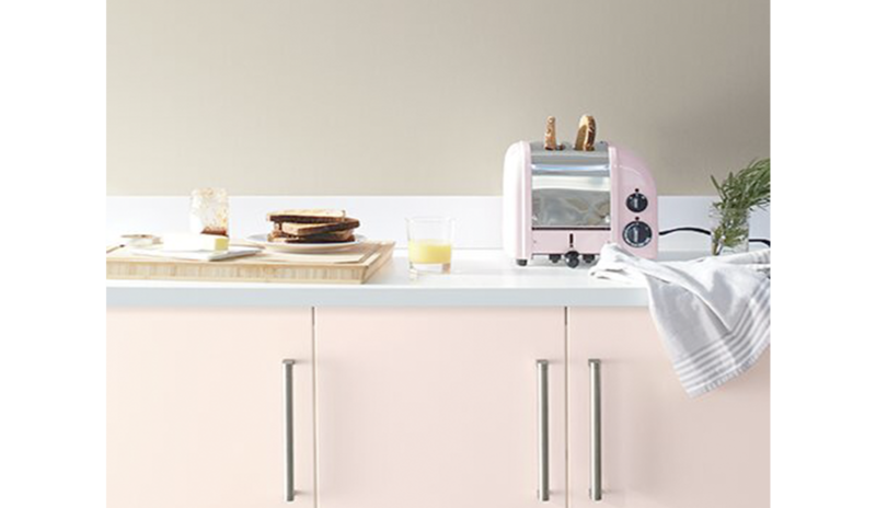 Greige walls with light pink cabinets and white countertops featuring kitchen.