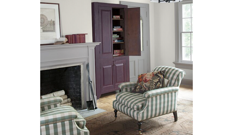 A sitting area with walls painted in Barren Plain 2111-60, fireplace, and two green striped chairs.