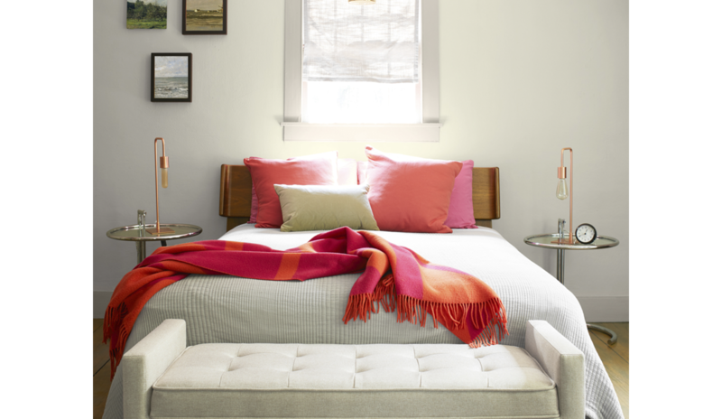 A neutral colored bedroom with walls painted in Natural Cream OC-14, bold red throw pillows
