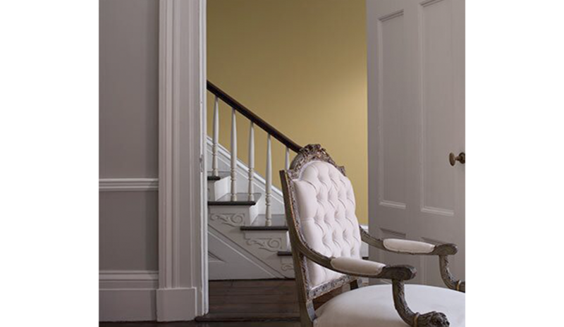 A living room in light gray features a door opening to a yellow-painted foyer. A living room in light gray features a door opening to a yellow-painted foyer.