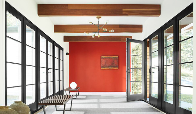 A white-painted hallway with a red accent wall, wood beam ceiling, black-trim windows and door. A white-painted hallway with a red accent wall, wood beam ceiling, black-trim windows and door.