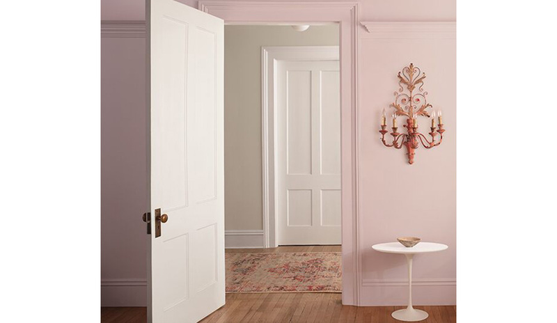 Light pink-painted walls with an open door leading out to a room with off-white-painted walls. Light pink-painted walls with an open door leading out to a room with off-white-painted walls.