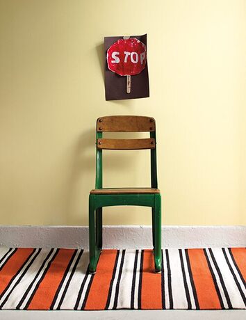 Green wooden school chair, soft yellow wall, hand-painted stop sign, and striped rug. Green wooden school chair, soft yellow wall, hand-painted stop sign, and striped rug.