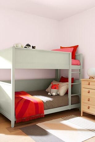 Pink-walled kids' room: bunk beds w/ red and gray bedding, wooden dresser, striped rug. Pink-walled kids' room: bunk beds w/ red and gray bedding, wooden dresser, striped rug.