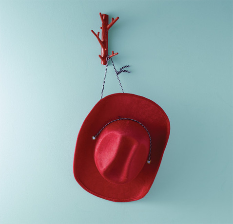 A pale blue wall frames a red cowboy hat. A pale blue wall frames a red cowboy hat.