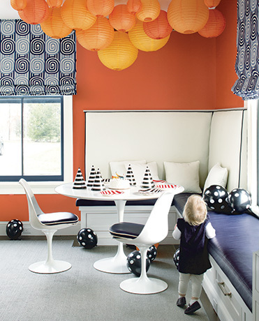 Orange-painted walls and paper lanterns surround a table with birthday hats. Orange-painted walls and paper lanterns surround a table with birthday hats.