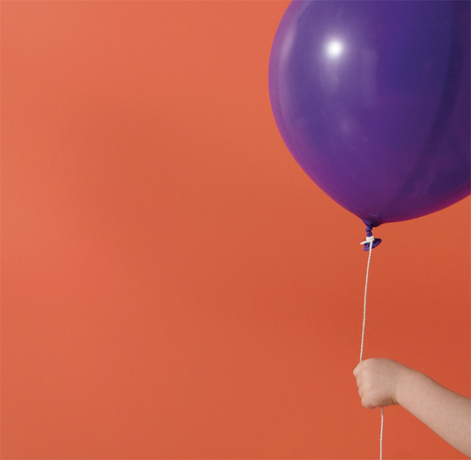 An orange-painted wall frames a purple balloon. An orange-painted wall frames a purple balloon.