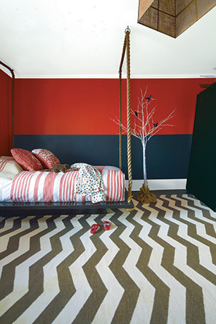 A kid's bedroom with a red and black painted wall features a swing bed. A kid's bedroom with a red and black painted wall features a swing bed.