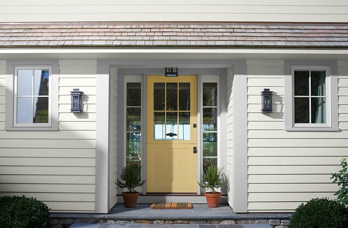 A white-painted house with a pretty yellow-gold front door, light gray trim
