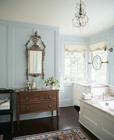 A light blue-painted bathroom with vintage mirror and sideboard.