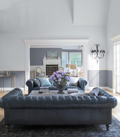 A serene living room in a combination of white and gray paint features two large leather couches. A serene living room in a combination of white and gray paint features two large leather couches.