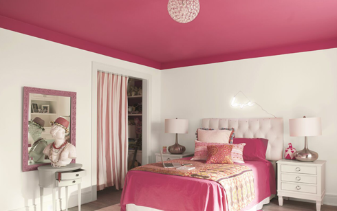 White bedroom walls with a bright pink ceiling and matching pink bedding with tables and lamps.