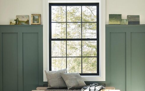 An inviting entryway with dark green-painted wainscoting, white walls and trim, a large window 