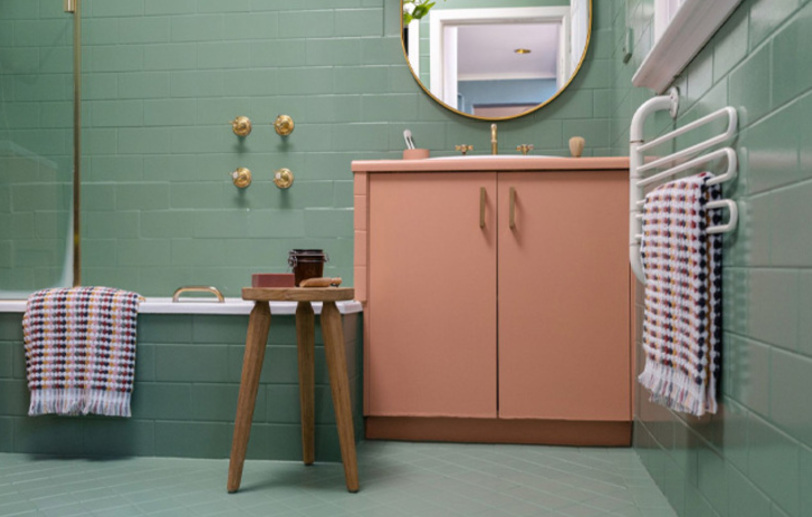 The bathroom tiles are painted in green color, there is a chair and a pink cabinet. The bathroom tiles are painted in green color, there is a chair and a pink cabinet.