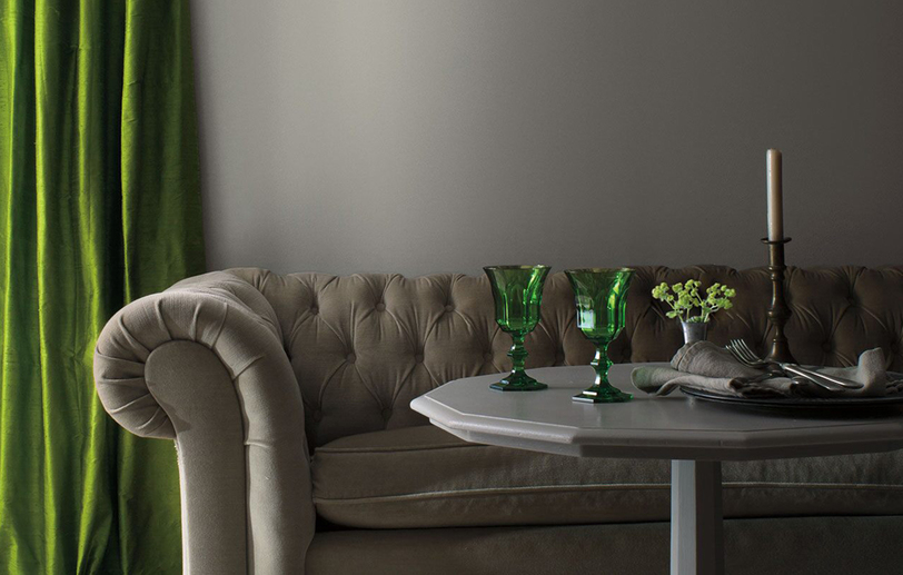 A living room with gray-painted walls, traditional gray couch, gray table with green accents. A living room with gray-painted walls, traditional gray couch, gray table with green accents.